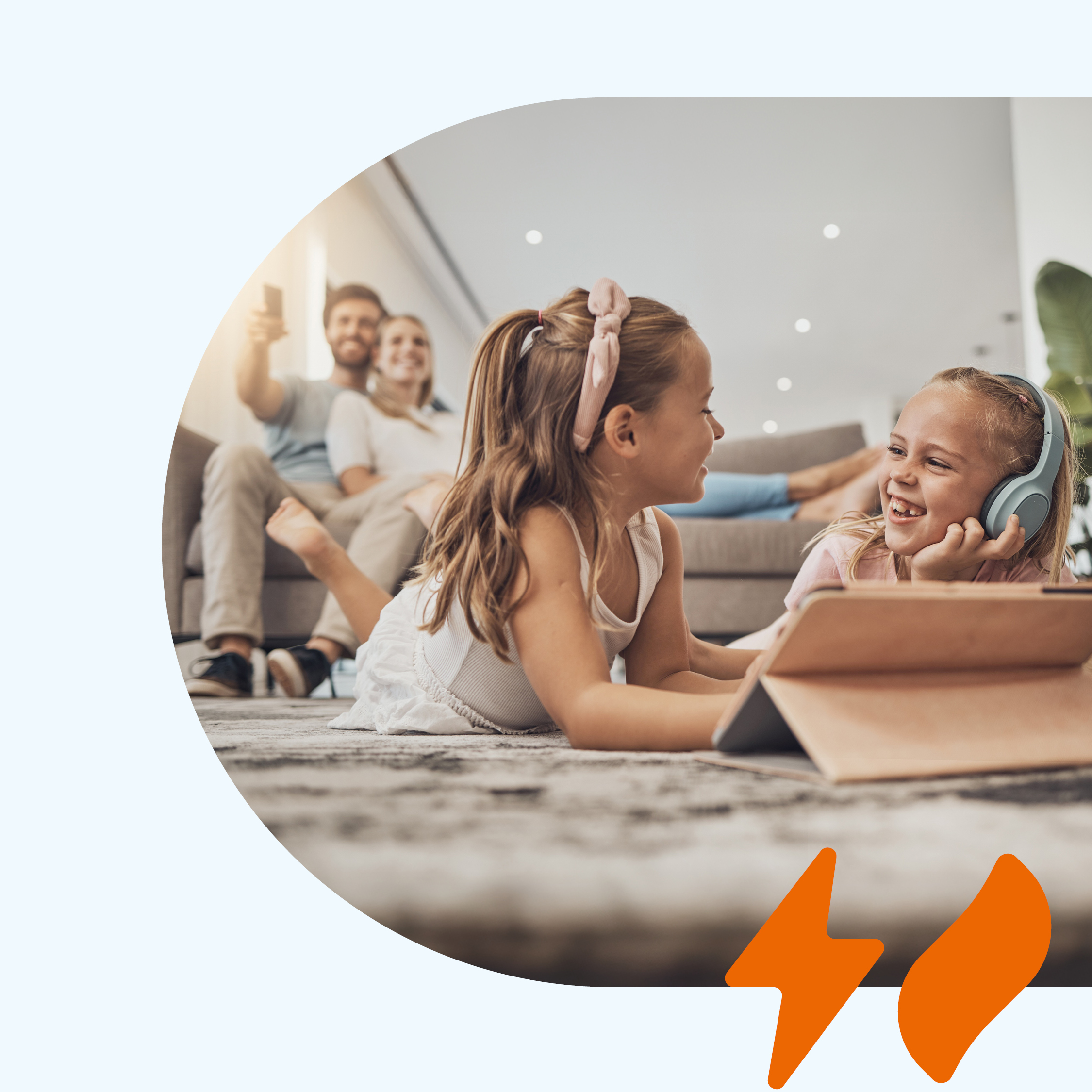 Eine fröhliche Familie im Wohnzimmer, die Kinder spielen auf dem Boden mit einem Tablet.